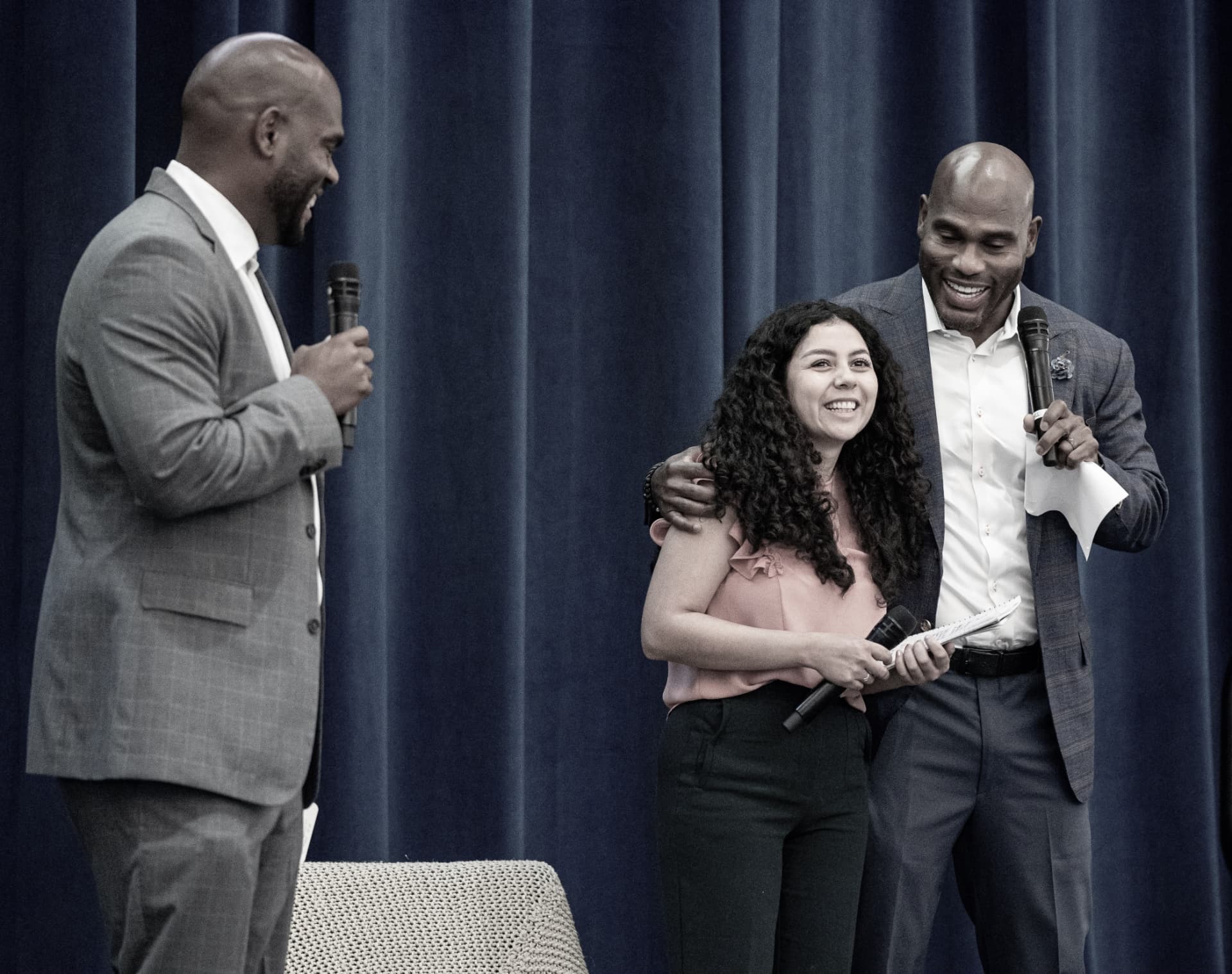 A smiling guest on stage with the hosts at The Gold Chair