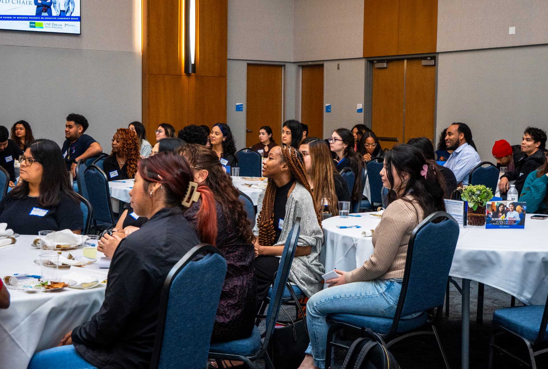 Attendees listening at round tables during The Gold Chair
