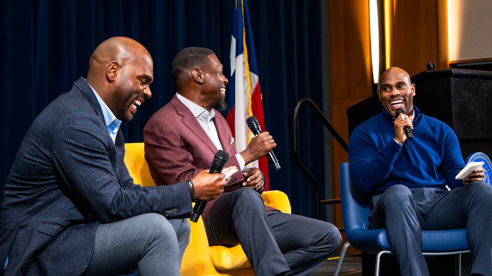 Guest speakers sharing a laugh on stage at The Gold Chair