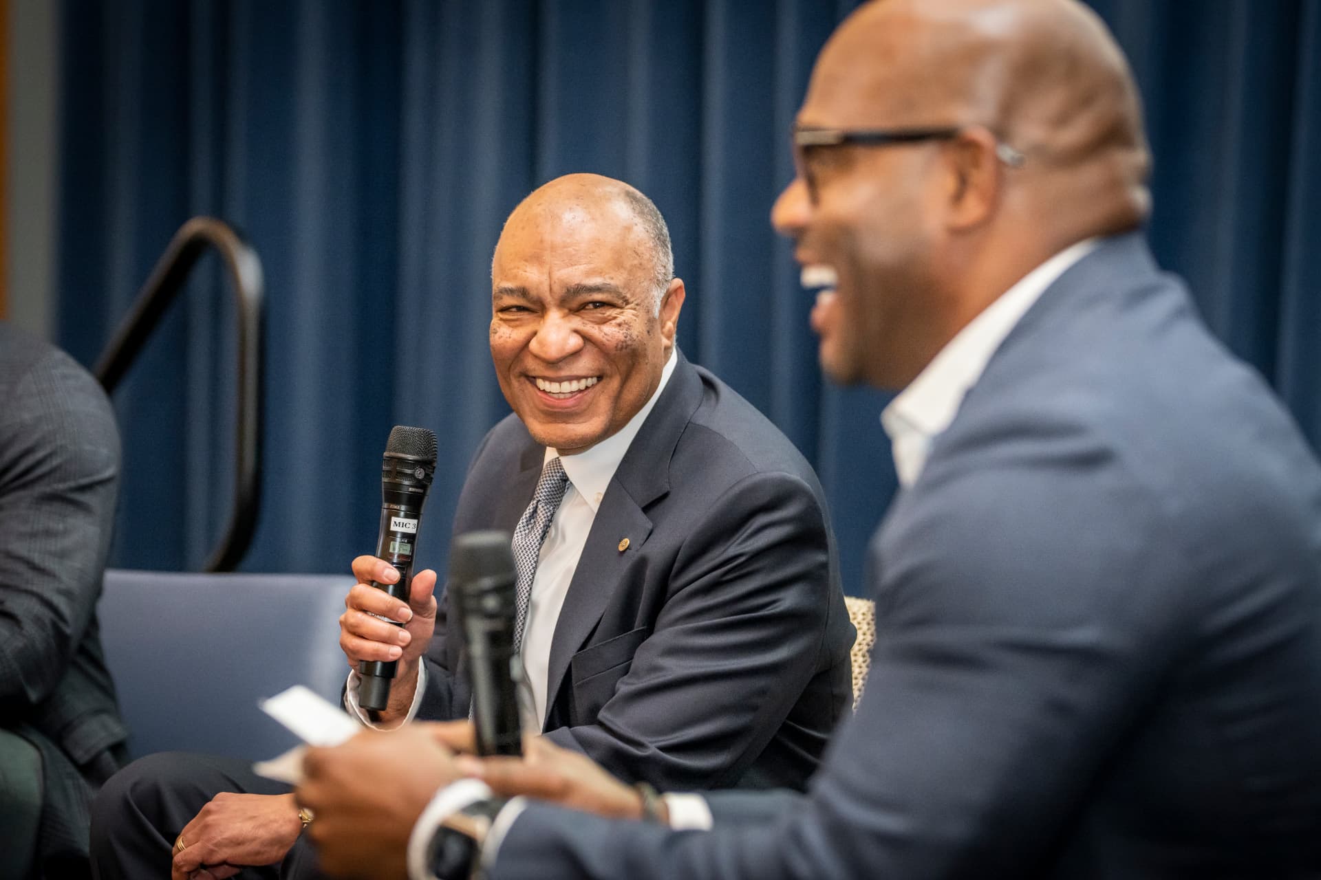 Two hosts sharing a laugh on stage at The Gold Chair